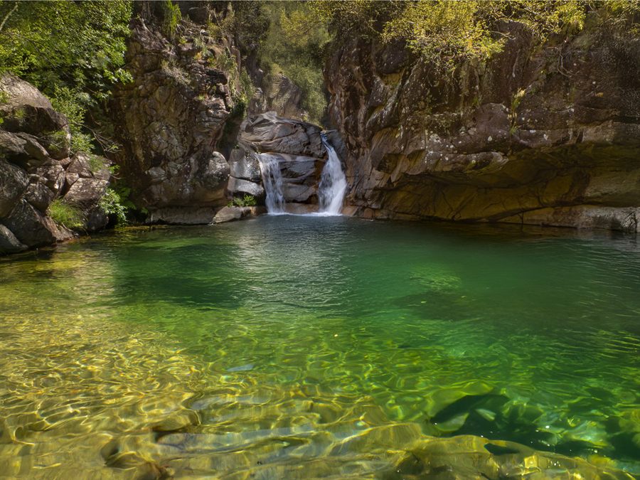 Natural pool with green water and a waterfall in Peneda-Gerês National Park